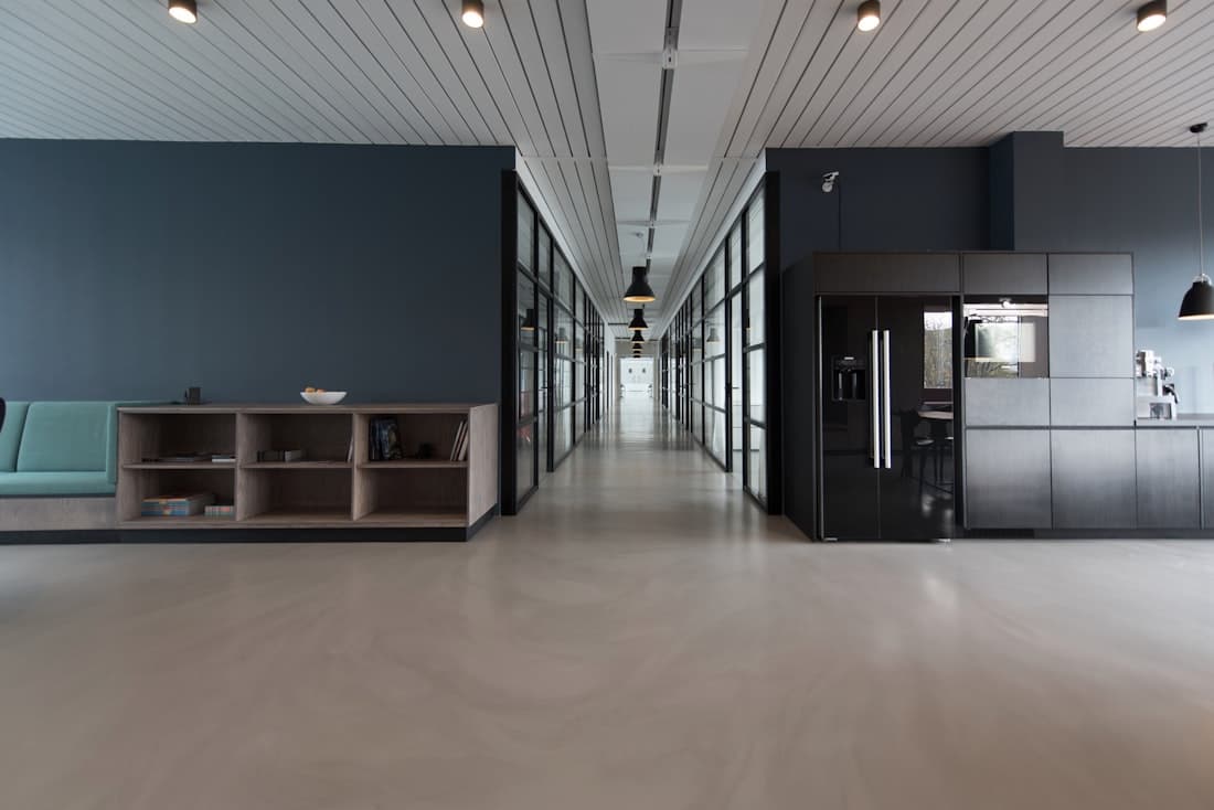 Open office corridor with concrete floors and a shared kitchen area